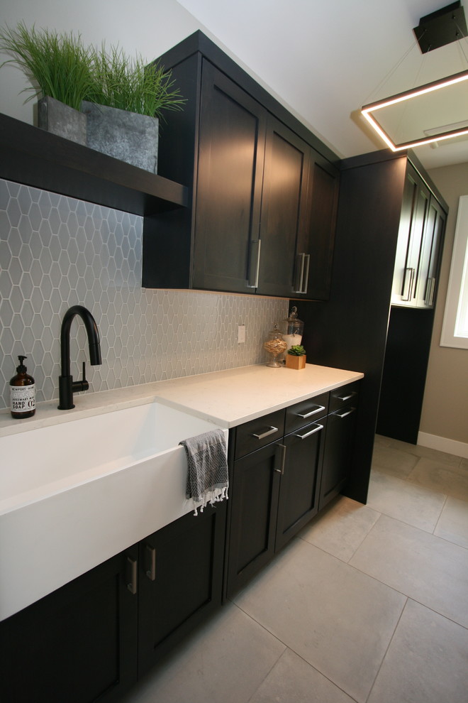 Example of a mid-sized transitional single-wall dedicated laundry room design in Seattle with shaker cabinets, black cabinets and quartz countertops