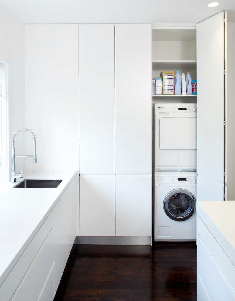 Moderner Hauswirtschaftsraum mit weißen Schränken und Waschmaschine und Trockner versteckt in Sydney