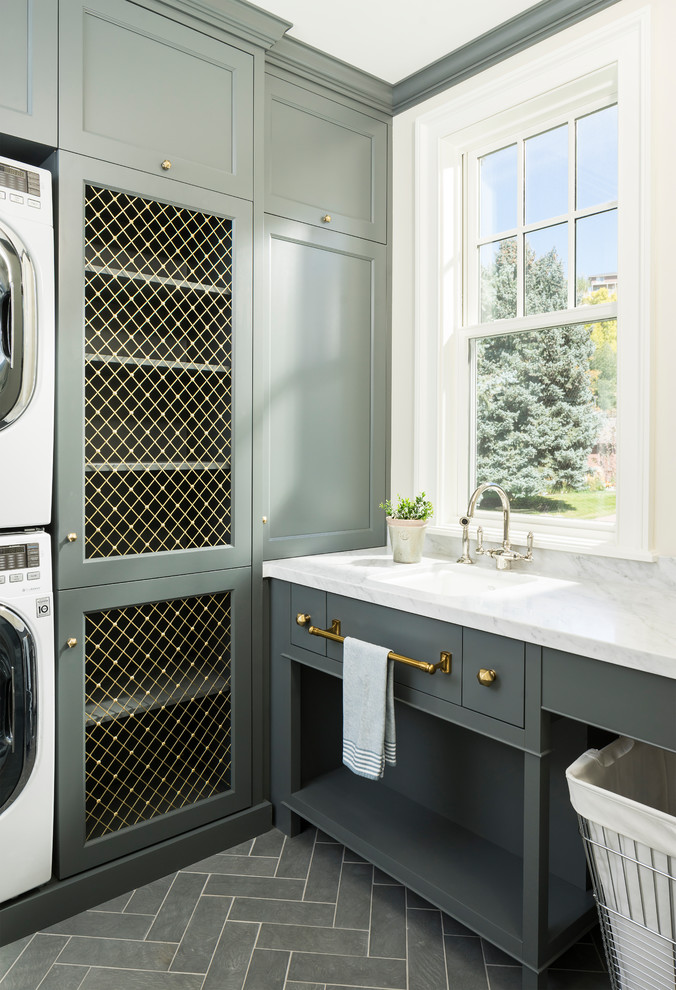 Immagine di una sala lavanderia chic con lavello a vasca singola, ante in stile shaker, ante grigie, lavatrice e asciugatrice a colonna e pavimento grigio