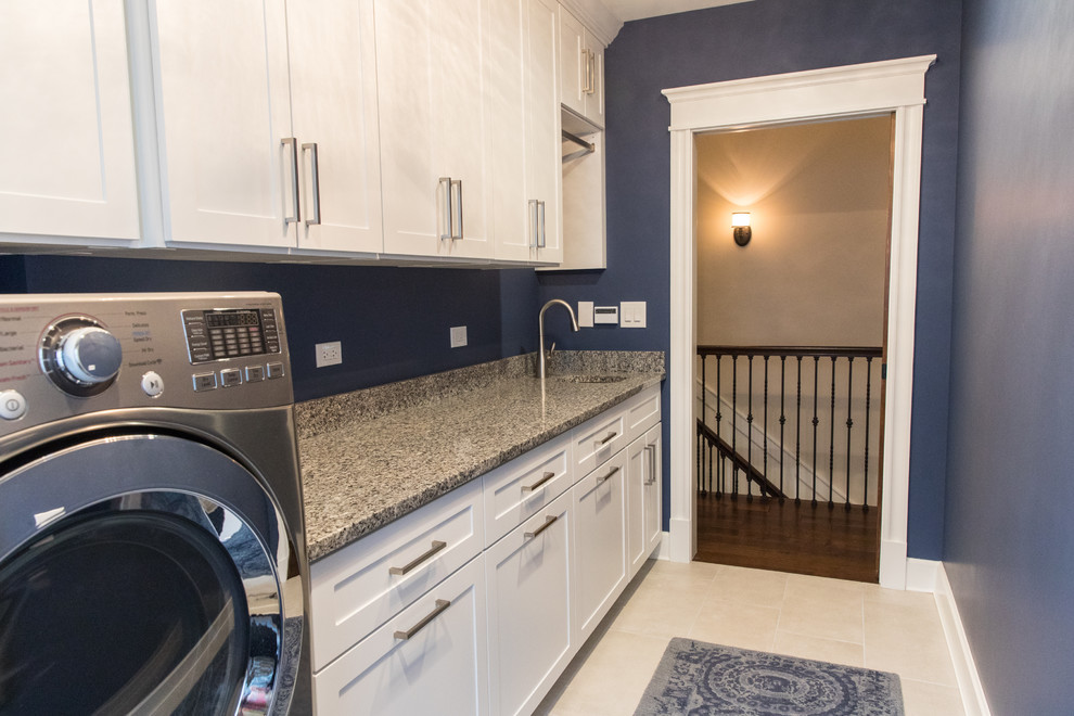 Mid-sized elegant single-wall porcelain tile and beige floor dedicated laundry room photo in Chicago with an undermount sink, shaker cabinets, white cabinets, granite countertops, blue walls and a side-by-side washer/dryer