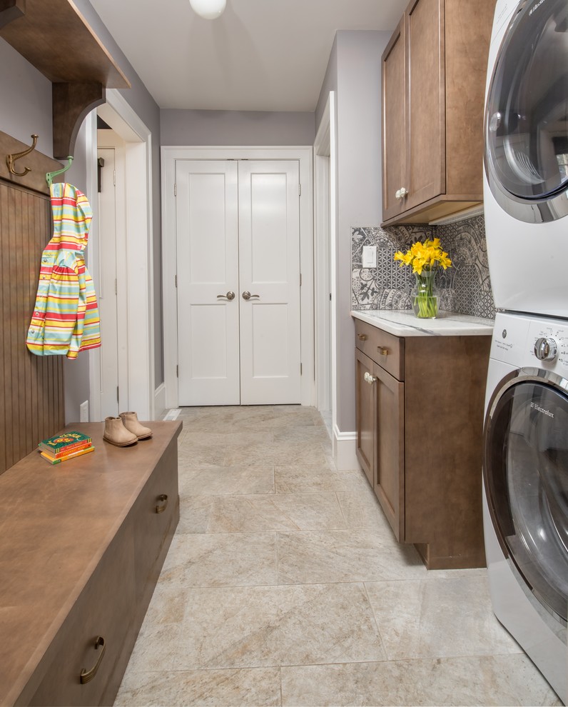 This is an example of a medium sized classic utility room in Boston with shaker cabinets, grey walls, a stacked washer and dryer, beige floors, engineered stone countertops, porcelain flooring and dark wood cabinets.