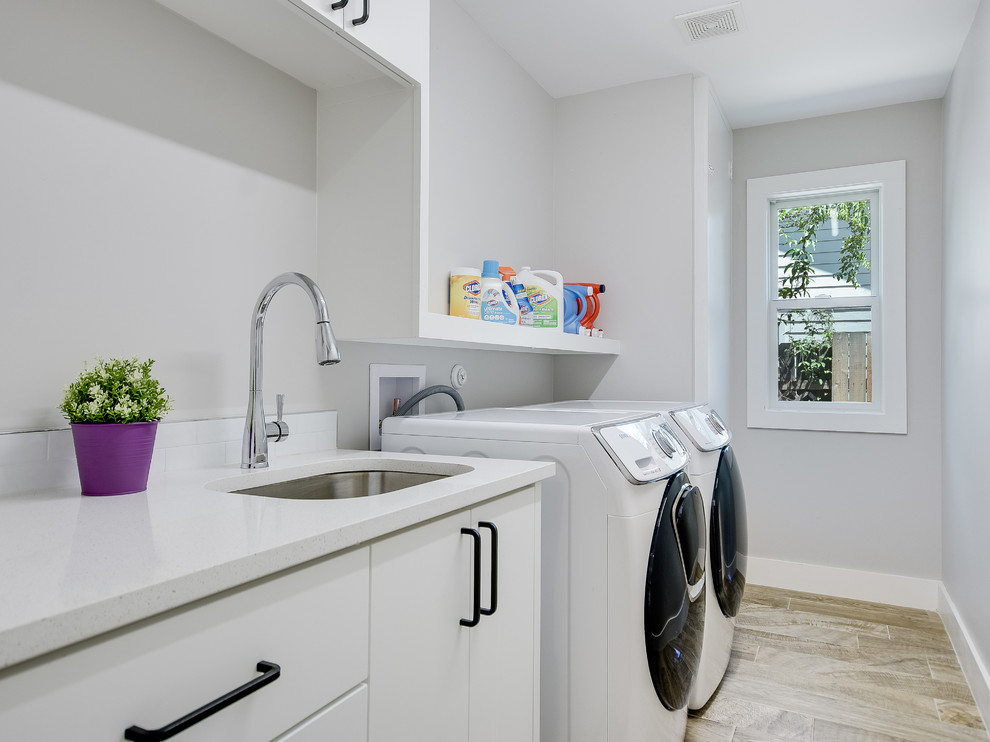 Idéer för mellanstora funkis parallella tvättstugor enbart för tvätt, med en undermonterad diskho, släta luckor, vita skåp, grå väggar, klinkergolv i keramik, en tvättmaskin och torktumlare bredvid varandra och brunt golv