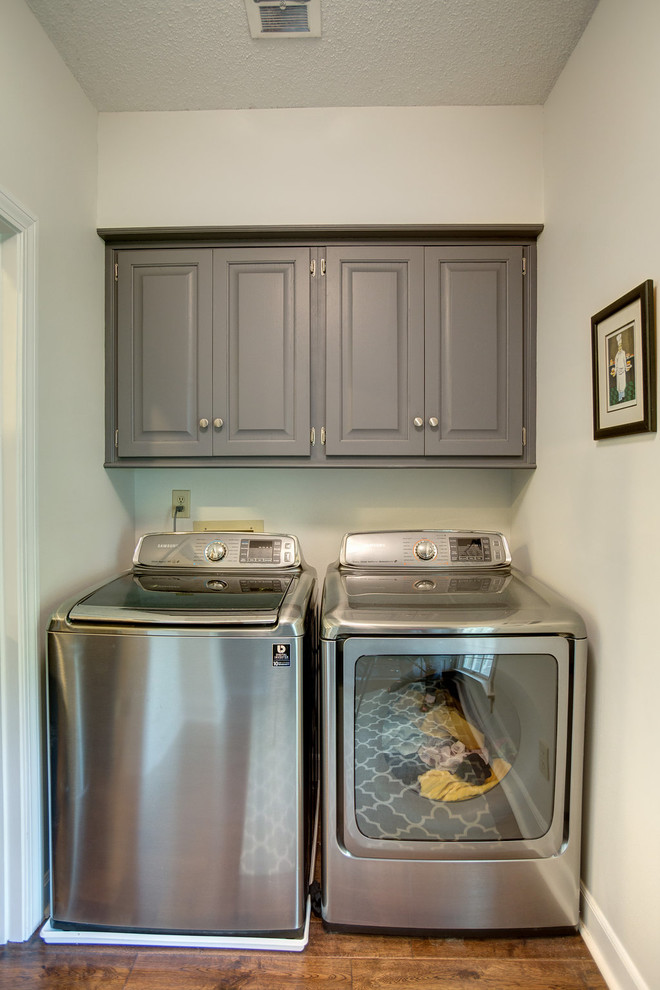 Mid-sized galley medium tone wood floor dedicated laundry room photo in Birmingham with raised-panel cabinets, gray cabinets, wood countertops, gray walls and a side-by-side washer/dryer