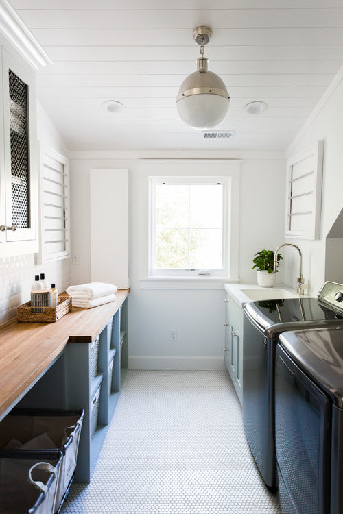 This is an example of a large beach style separated utility room in Salt Lake City with blue cabinets, wood worktops, white walls, a side by side washer and dryer, white floors and beige worktops.