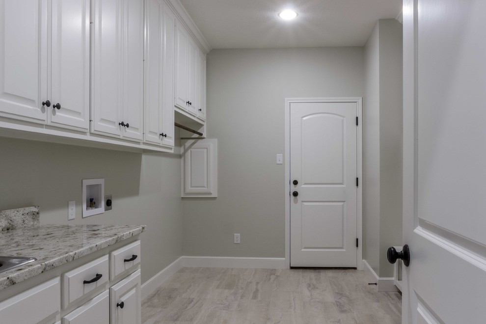 This is an example of a large classic galley utility room in Austin with an utility sink, raised-panel cabinets, white cabinets, granite worktops, beige walls, porcelain flooring and a side by side washer and dryer.