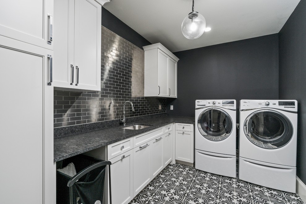 Klassische Waschküche in L-Form mit Unterbauwaschbecken, Kassettenfronten, weißen Schränken, schwarzer Wandfarbe, Waschmaschine und Trockner nebeneinander, schwarzem Boden und schwarzer Arbeitsplatte in Atlanta