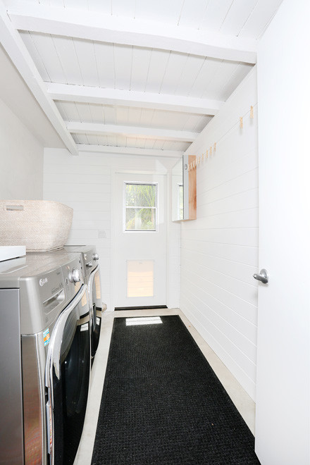 Idee per una sala lavanderia minimalista con pareti bianche, pavimento in cemento e lavatrice e asciugatrice affiancate