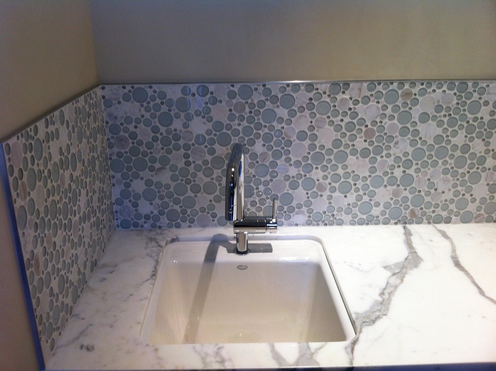 Inspiration för en mellanstor vintage l-formad tvättstuga enbart för tvätt, med en nedsänkt diskho, luckor med infälld panel, vita skåp, marmorbänkskiva, grå väggar, mellanmörkt trägolv och en tvättpelare