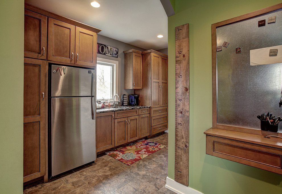 Utility room - large craftsman single-wall ceramic tile utility room idea in Grand Rapids with a drop-in sink, medium tone wood cabinets, solid surface countertops, green walls and a stacked washer/dryer