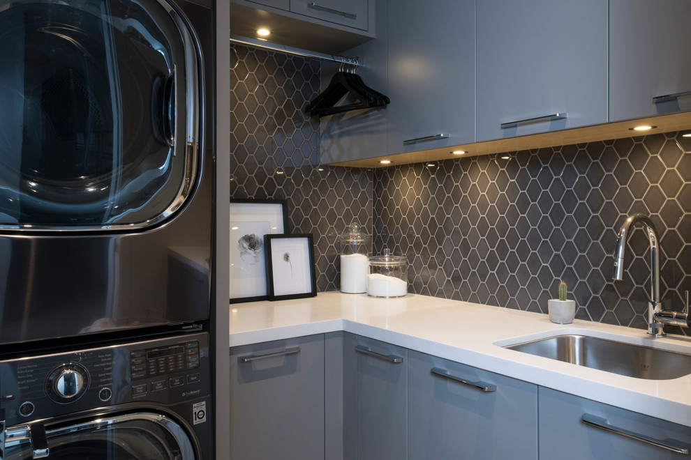 Mittelgroße Moderne Waschküche in L-Form mit Unterbauwaschbecken, flächenbündigen Schrankfronten, grauen Schränken, grauer Wandfarbe, Porzellan-Bodenfliesen, Waschmaschine und Trockner gestapelt, weißem Boden und weißer Arbeitsplatte in Vancouver