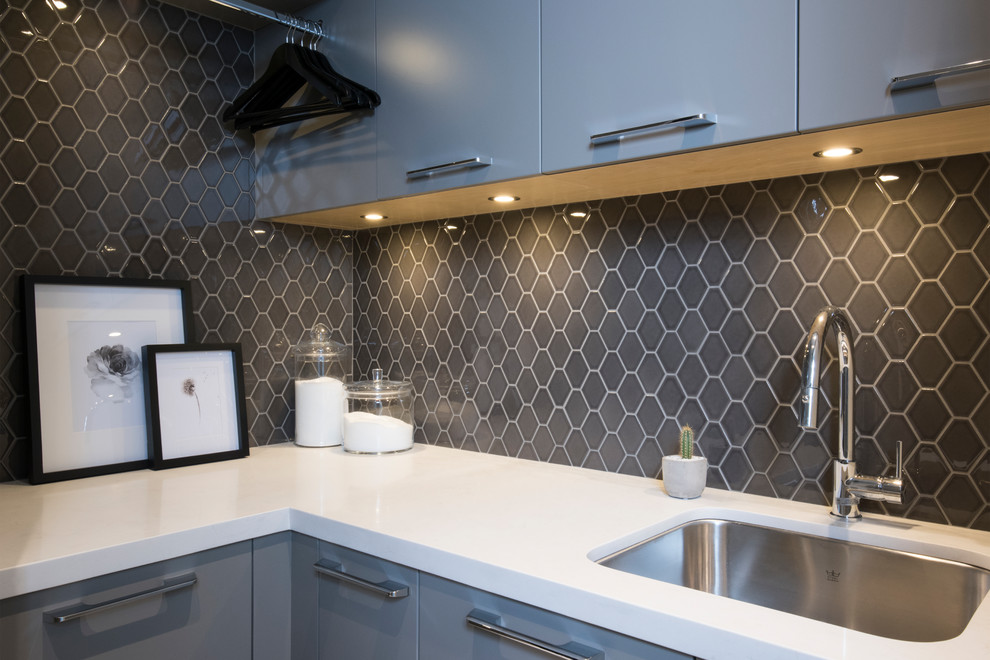 Inspiration for a mid-sized contemporary l-shaped porcelain tile and white floor dedicated laundry room remodel in Vancouver with an undermount sink, flat-panel cabinets, gray cabinets, gray walls, a stacked washer/dryer and white countertops