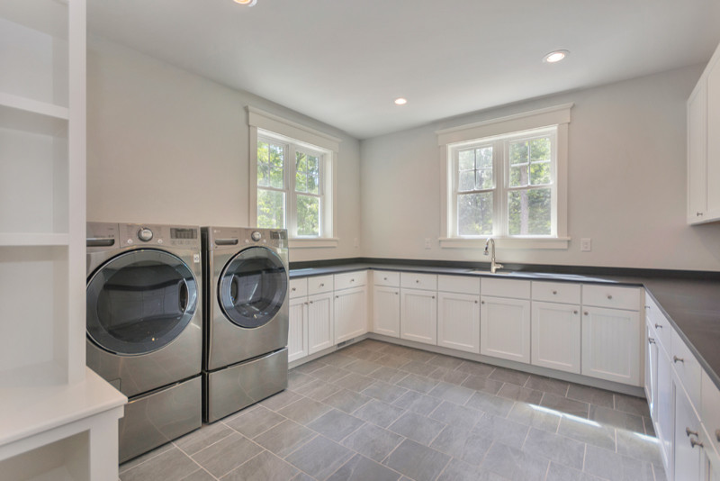 Foto di una grande sala lavanderia american style con lavello sottopiano, ante bianche, pavimento con piastrelle in ceramica e lavatrice e asciugatrice affiancate