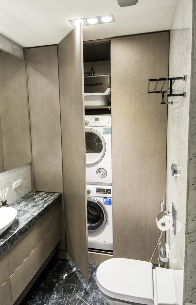 Imagen de armario lavadero actual pequeño con armarios con paneles lisos y lavadora y secadora apiladas