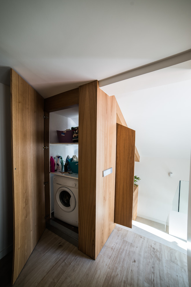 Imagen de armario lavadero lineal nórdico pequeño con puertas de armario de madera oscura, armarios abiertos y suelo de madera en tonos medios