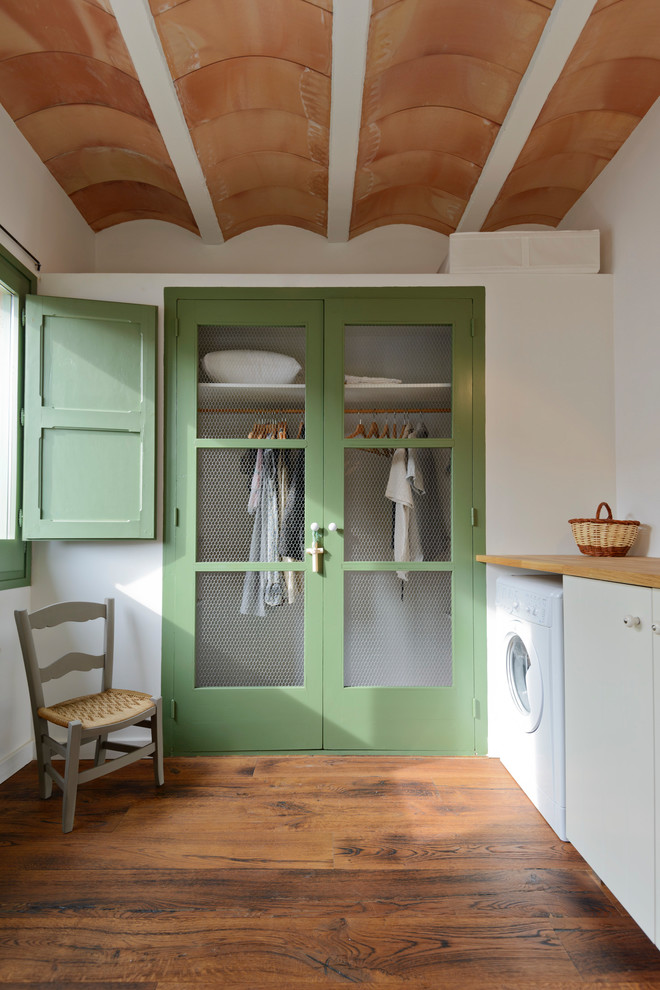 Idee per una sala lavanderia mediterranea di medie dimensioni con ante lisce, ante bianche, top in legno, parquet scuro, pavimento marrone e pareti bianche