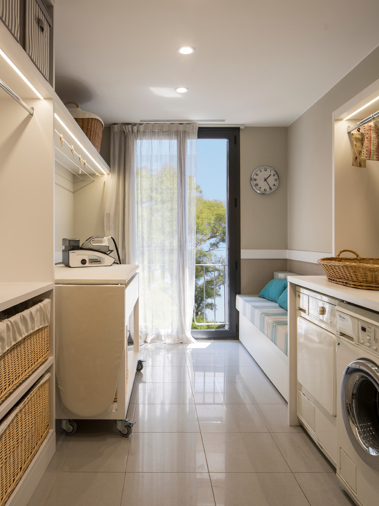 バルセロナにある中くらいな北欧スタイルのおしゃれな洗濯室 (ll型、オープンシェルフ、左右配置の洗濯機・乾燥機、白いキャビネット) の写真