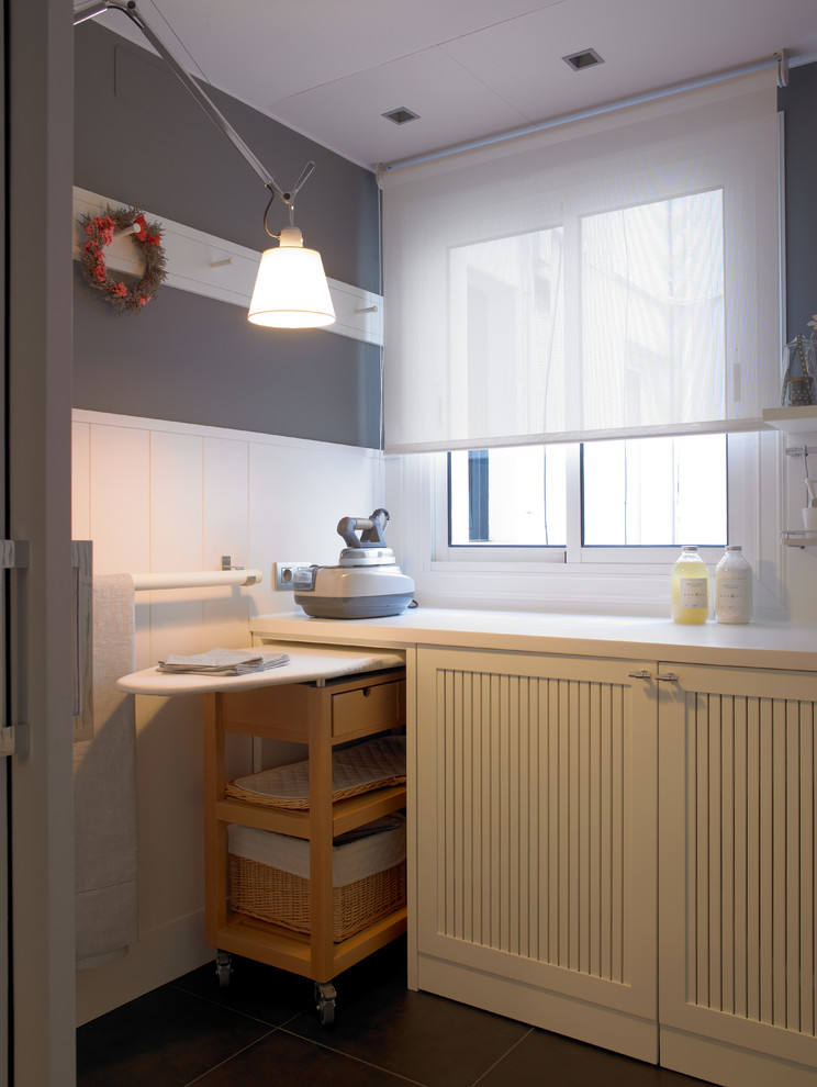 Example of a mid-sized trendy laundry room design in Barcelona with white cabinets