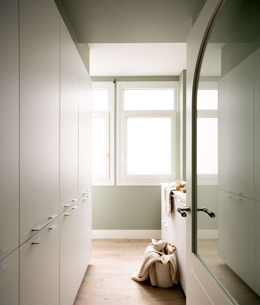 Exempel på en mellanstor klassisk vita linjär vitt tvättstuga enbart för tvätt, med en undermonterad diskho, släta luckor, vita skåp, bänkskiva i kvarts, gröna väggar, laminatgolv, tvättmaskin och torktumlare byggt in i ett skåp och beiget golv