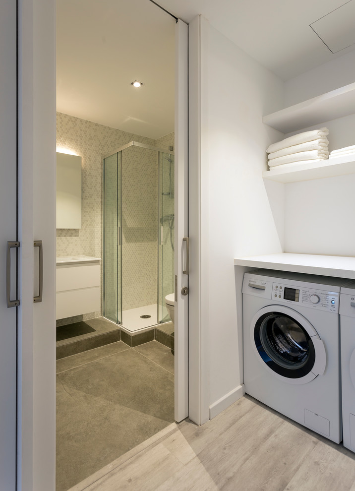 Small contemporary single-wall separated utility room in Barcelona with white walls, light hardwood flooring and a side by side washer and dryer.