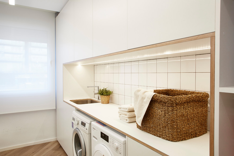 Mittelgroße Skandinavische Waschküche mit Unterbauwaschbecken, weißer Wandfarbe und Waschmaschine und Trockner nebeneinander in Barcelona