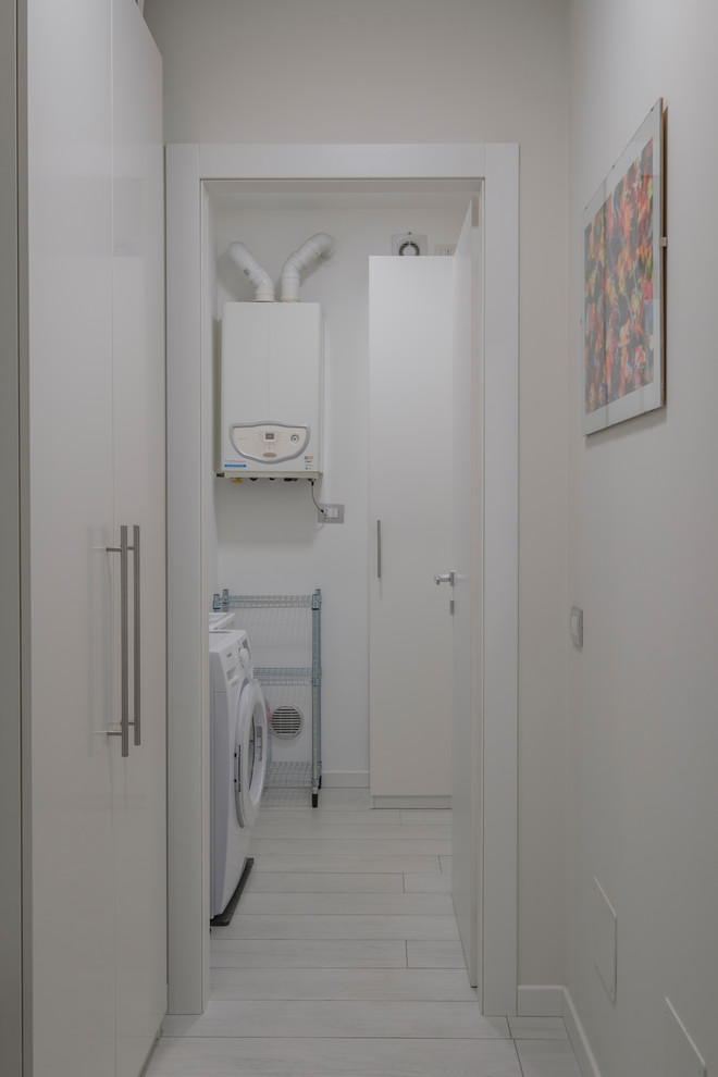 Foto di una piccola lavanderia multiuso minimalista con lavatoio, ante lisce, ante bianche, pareti grigie, pavimento in gres porcellanato, lavatrice e asciugatrice a colonna e pavimento bianco