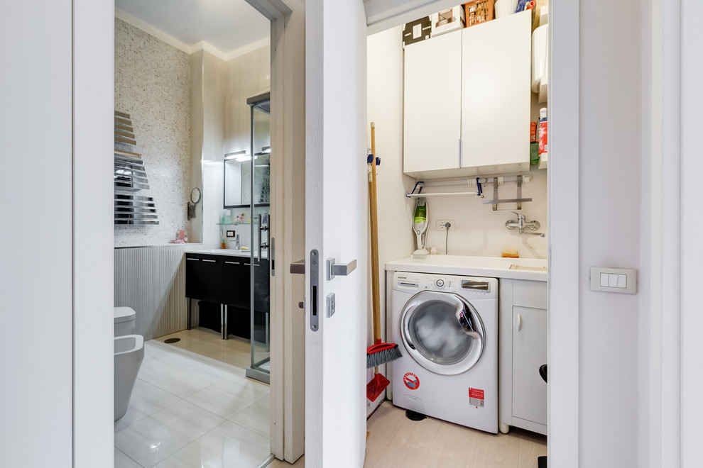 Imagen de lavadero multiusos moderno pequeño con fregadero encastrado, armarios con paneles lisos, puertas de armario blancas, paredes beige, suelo laminado, lavadora y secadora juntas y suelo beige