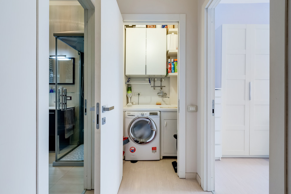 Esempio di una piccola lavanderia multiuso minimalista con ante lisce, ante bianche, pareti beige, pavimento in laminato, lavatrice e asciugatrice affiancate e pavimento beige