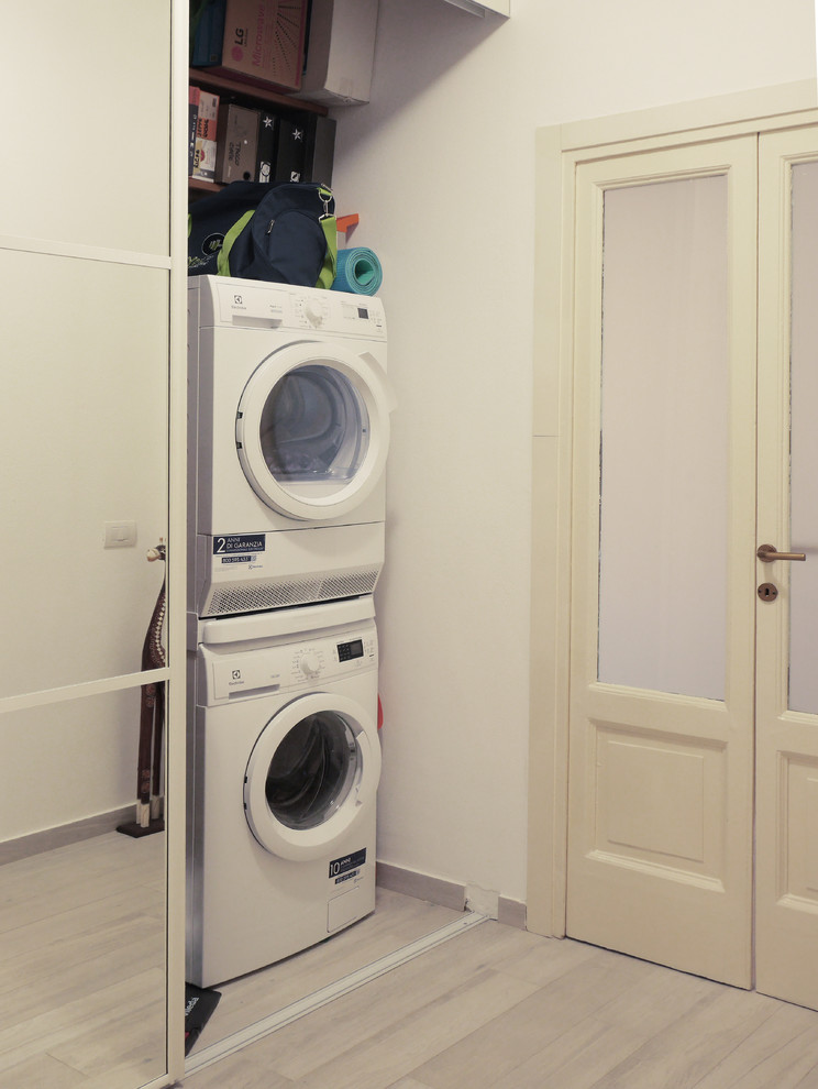 Example of a small minimalist galley porcelain tile and beige floor laundry closet design in Milan with flat-panel cabinets, white cabinets, white walls and a concealed washer/dryer