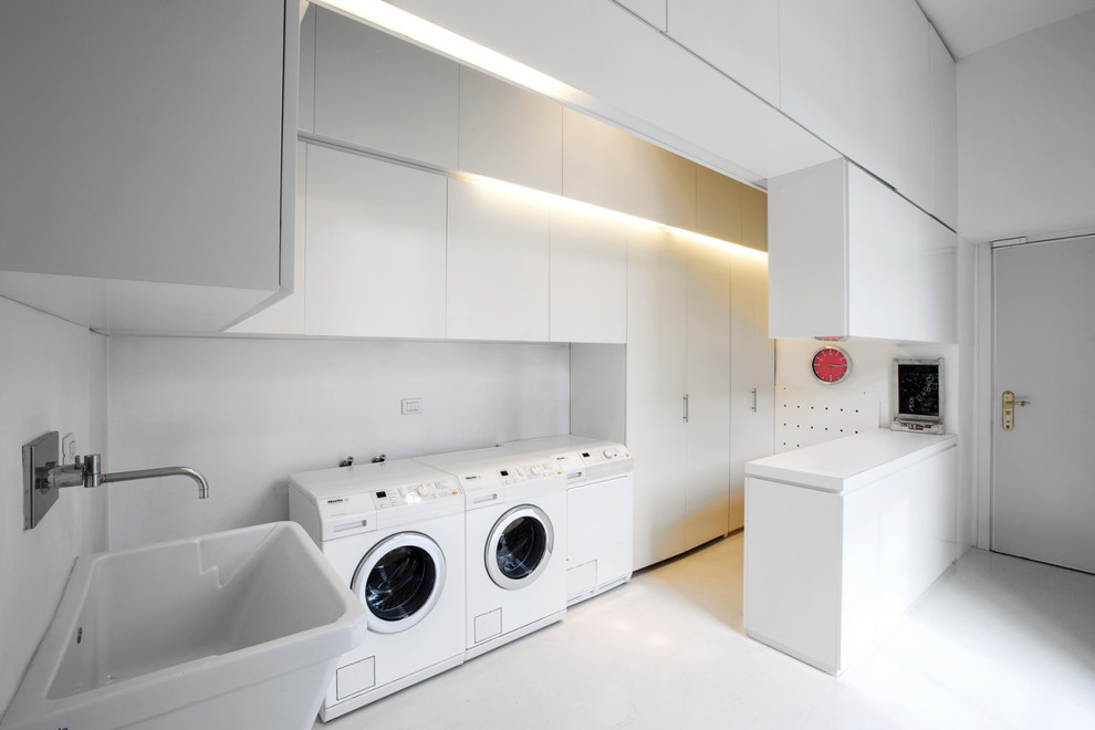 Immagine di una grande sala lavanderia design con lavello a vasca singola, ante lisce, ante bianche, pareti bianche, pavimento in gres porcellanato e lavatrice e asciugatrice affiancate