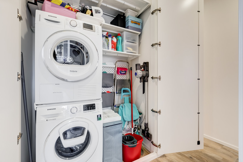 Immagine di una piccola lavanderia multiuso moderna con ante lisce, ante bianche, pareti bianche, pavimento in gres porcellanato e lavatrice e asciugatrice a colonna