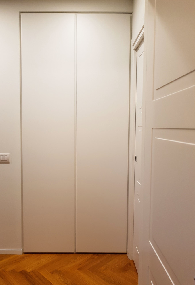 Foto de cuarto de lavado en U actual pequeño con armarios abiertos, puertas de armario blancas, paredes blancas, suelo de baldosas de porcelana, lavadora y secadora apiladas y suelo gris