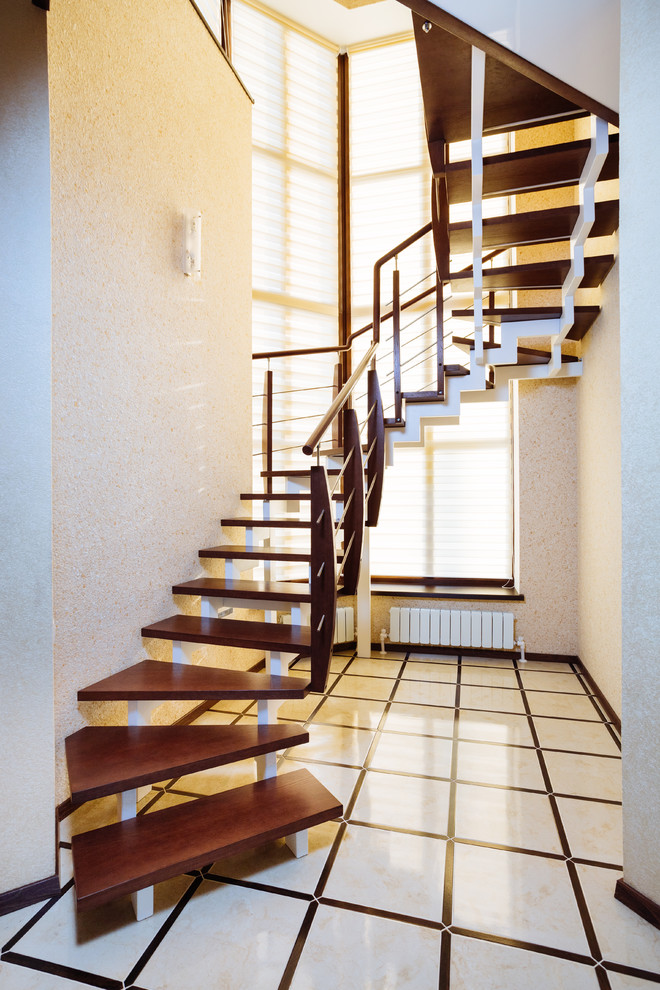 Стильный дизайн: изогнутая лестница среднего размера в современном стиле с деревянными ступенями и перилами из смешанных материалов - последний тренд