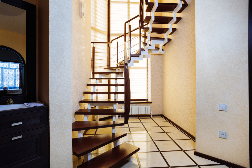На фото: изогнутая лестница среднего размера в современном стиле с деревянными ступенями и перилами из смешанных материалов с