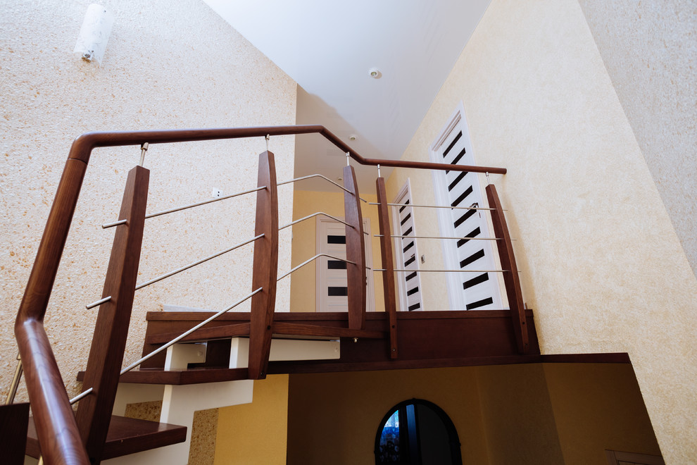 На фото: изогнутая лестница среднего размера в современном стиле с деревянными ступенями и перилами из смешанных материалов