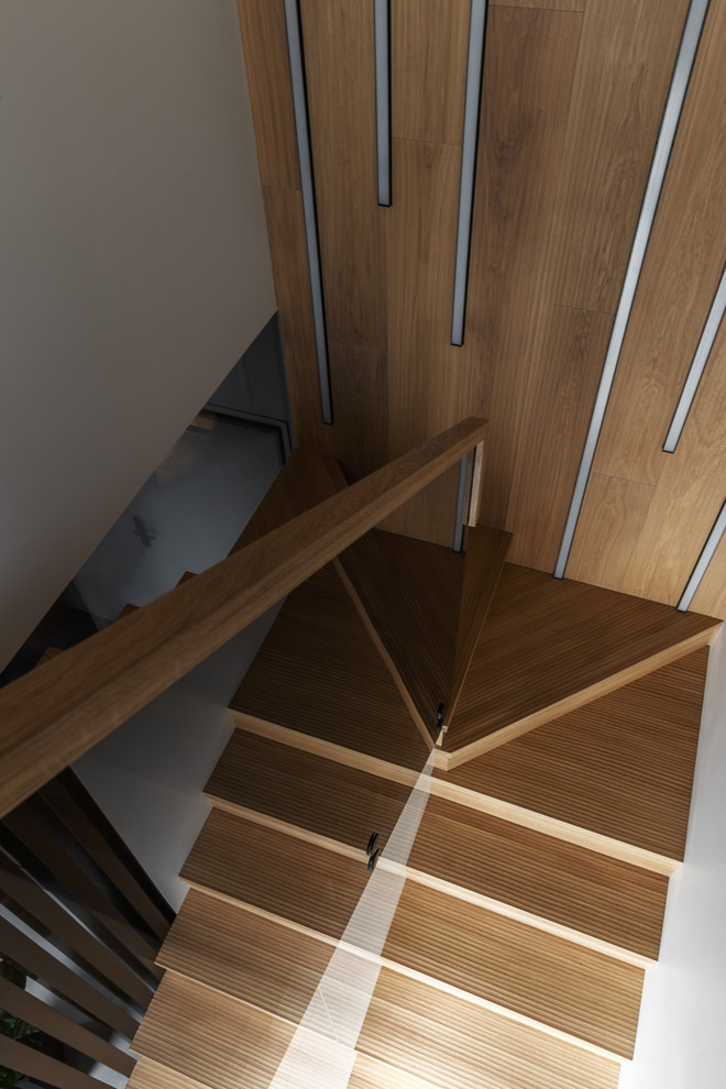 На фото: п-образная деревянная лестница среднего размера в современном стиле с деревянными ступенями и стеклянными перилами с