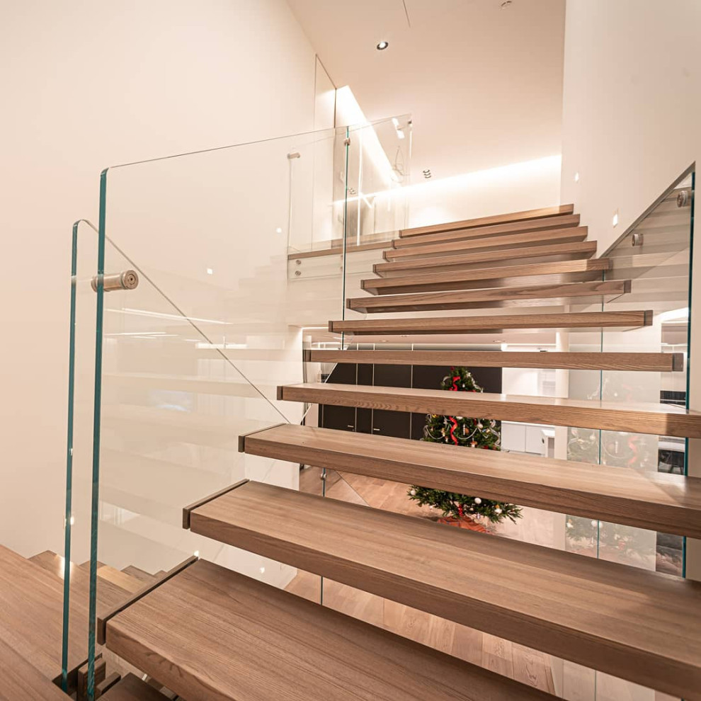 Cette image montre un escalier design en U de taille moyenne avec des marches en bois et un garde-corps en verre.