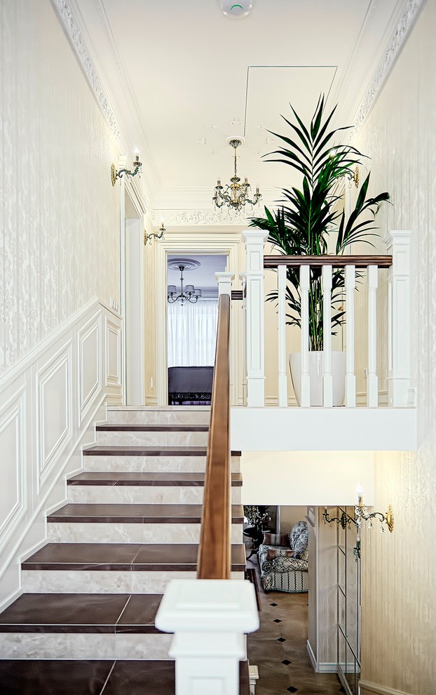 Diseño de escalera en U tradicional de tamaño medio con escalones con baldosas, contrahuellas con baldosas y/o azulejos y barandilla de madera