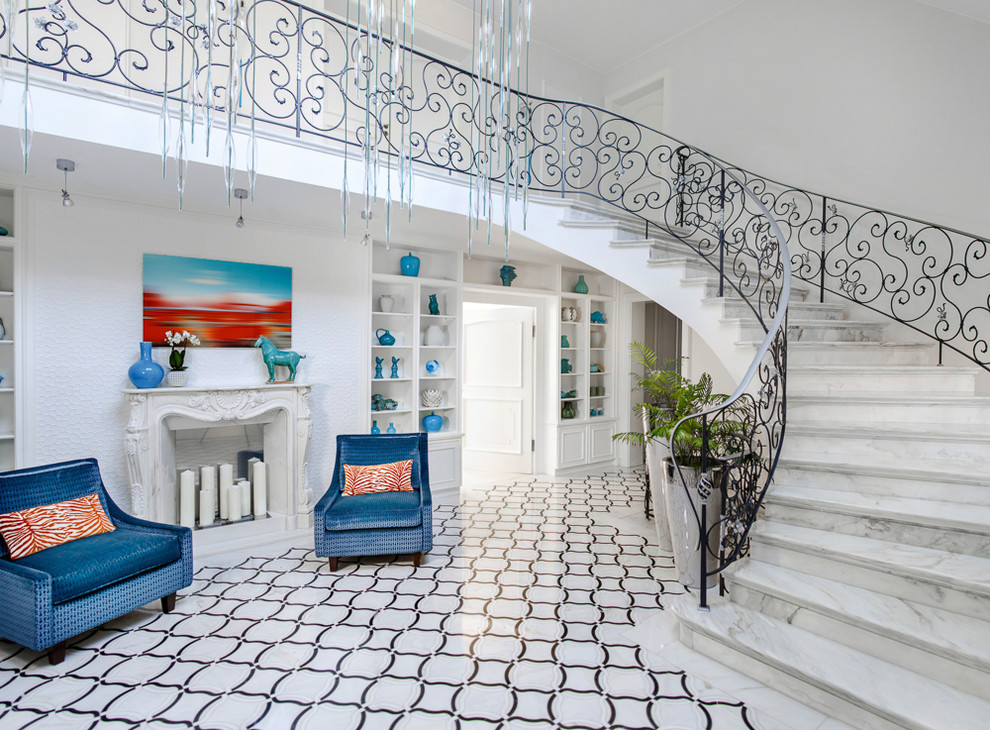 Источник вдохновения для домашнего уюта: огромная изогнутая лестница в классическом стиле с мраморными ступенями, подступенками из мрамора и металлическими перилами
