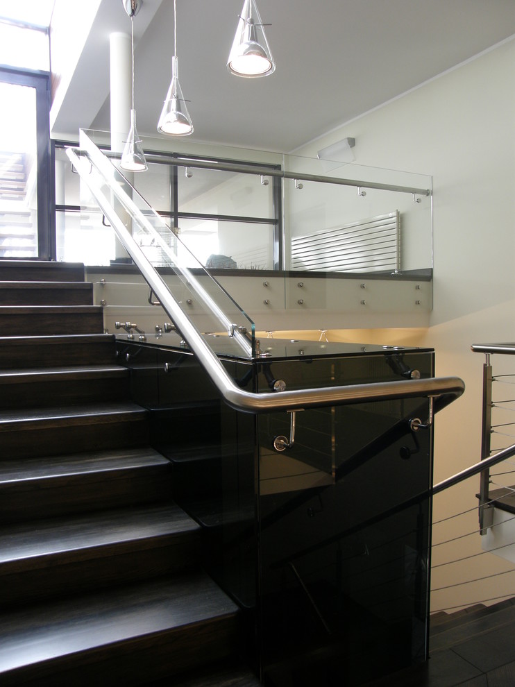 Aménagement d'un escalier contemporain en U avec des marches en bois, des contremarches en bois et un garde-corps en verre.