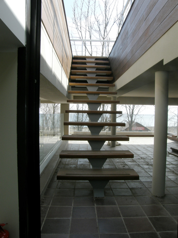 Ispirazione per una scala a rampa dritta contemporanea con pedata in legno, alzata in metallo e parapetto in vetro