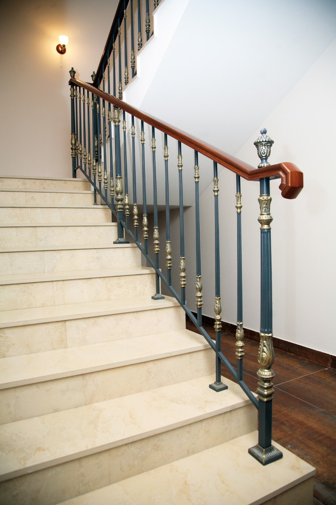 Diseño de escalera en U mediterránea grande con escalones de mármol, contrahuellas de mármol y barandilla de madera