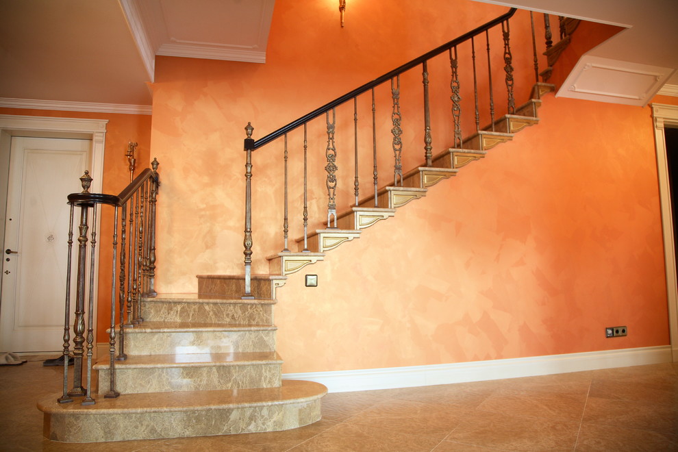 Idée de décoration pour un grand escalier méditerranéen en L et marbre avec des contremarches en marbre et un garde-corps en bois.