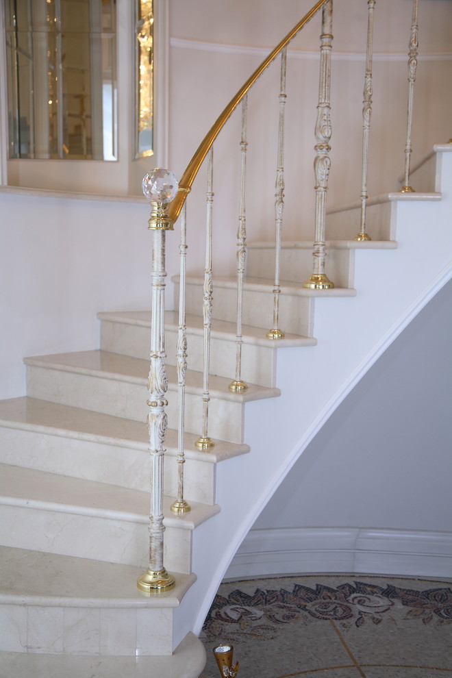 Источник вдохновения для домашнего уюта: большая изогнутая лестница в средиземноморском стиле с мраморными ступенями, подступенками из мрамора и металлическими перилами