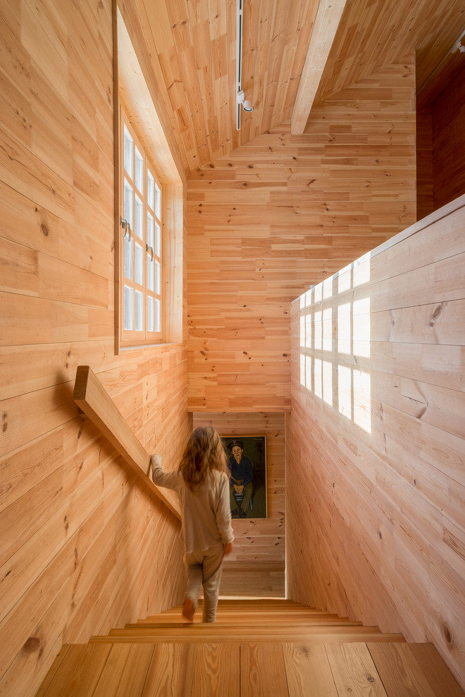 На фото: большая прямая деревянная лестница в стиле кантри с деревянными ступенями и деревянными перилами