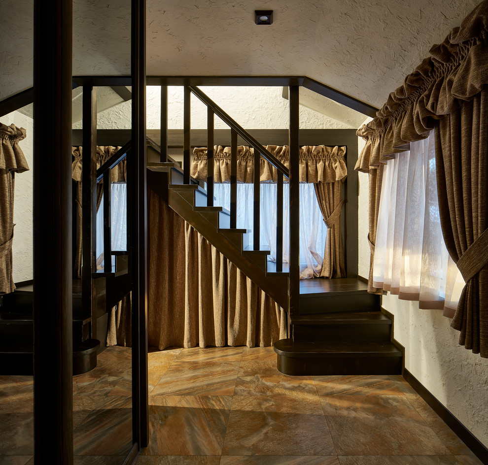 Diseño de escalera curva de estilo de casa de campo pequeña con escalones de madera, contrahuellas de madera y barandilla de madera