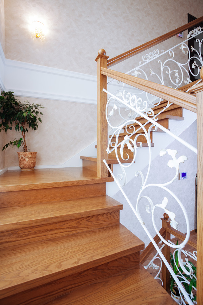 Idée de décoration pour un grand escalier tradition en U avec des marches en bois, des contremarches en bois et un garde-corps en matériaux mixtes.