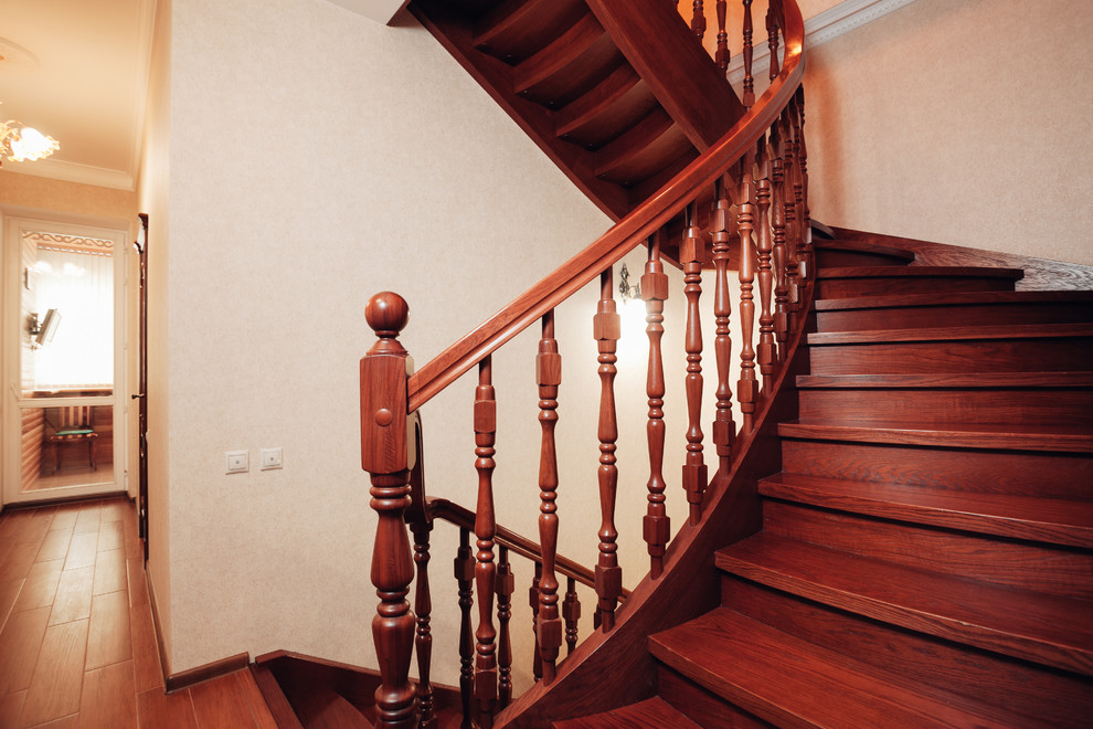 Inspiration pour un escalier courbe traditionnel de taille moyenne avec des marches en bois, des contremarches en bois et un garde-corps en bois.
