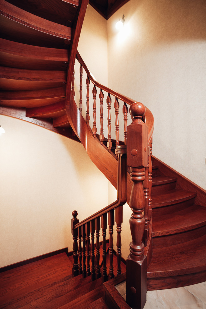 Imagen de escalera curva tradicional de tamaño medio con escalones de madera, contrahuellas de madera y barandilla de madera