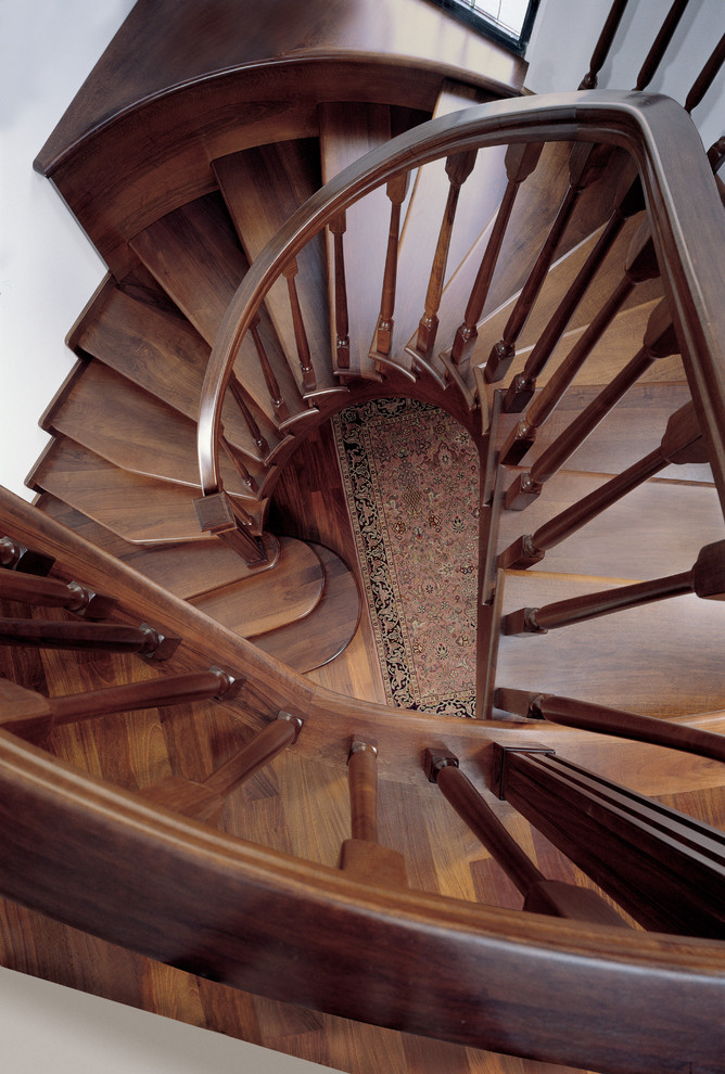 Стильный дизайн: большая изогнутая деревянная лестница в стиле рустика с деревянными ступенями и деревянными перилами - последний тренд