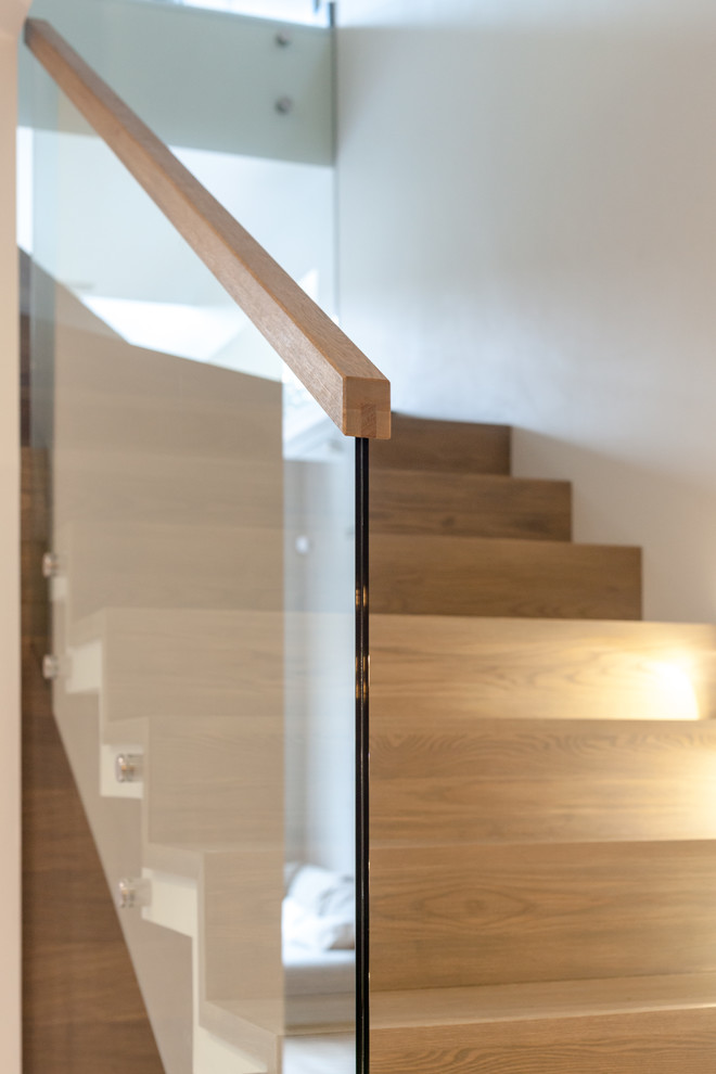 Свежая идея для дизайна: большая угловая деревянная лестница в современном стиле с деревянными ступенями и стеклянными перилами - отличное фото интерьера